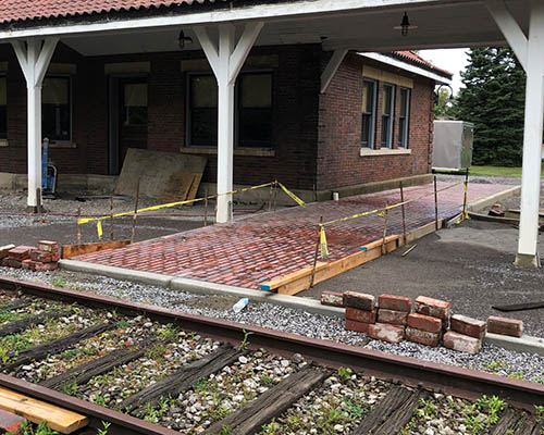 A new brick sidewalk leads pedestrians to the railroad tracks