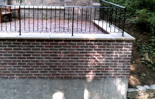 Salvaged bricks create a veneer on this patio retaining wall