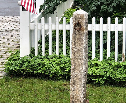 This antique hithcing post is wonderfully placed to highlight the surrounding landscape and picket fence.